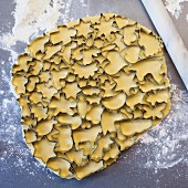 Many cookie cutters on rolled out cookie dough