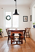 Wooden table with chunky legs and old chairs in bright dining room