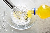 Fizzy orange lemonade being poured into dough ingredients