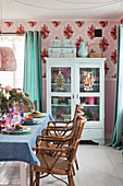 Set dining table in front of display cabinet against pink wall