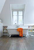 Free-standing bathrub in white bedroom with dormer window