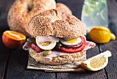 A bagel sandwich with turkey breast, tomato and egg