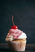A homemade cupcake topped with a cocktail cherry