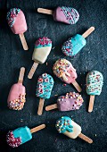 Cake pops in the shape of ice lollies with brightly coloured icing (seen from above)