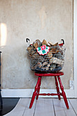 Firewood in wire basket on old red chair