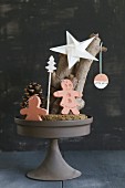 Christmas arrangement of gingerbread men made from clay and paper star on cake stand