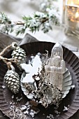 Christmas arrangement of antique glass Father Christmas and silver pine cones in tart tin
