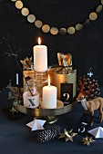 Original Advent arrangement on golden cake stand with garland, Advent star, stag ornament and gifts in gold paper against black background