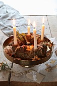 A traditional advent wreath on a golden stand with a hand painted label on a rustic table