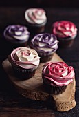 Süsse Rosen-Cupcakes auf Holzbrett