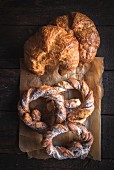 Sweet croissants and pretzels served on wooden table
