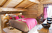 Gingham blanket on bed in rustic bedroom of log cabin