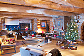 Christmas tree and arrangements of candles in living room of log cabin