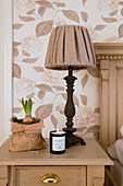 Table lamp, sprouting hyacinth in paper bag and candle on bedside table