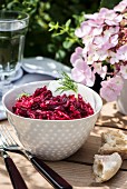 Red beet orzotto in a small bowl on a table outdoors