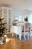 Gedeckter Tisch neben dem Weihnachtsbaum mit gemütlicher Beleuchtung