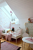 Bed with metal frame below skylight in girl's bedroom