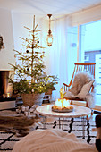 Kerzendeko auf dem Couchtisch vor dem Weihnachtsbaum im gemütlichen Wohnzimmer