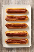 Chocolate eclairs on a serving plate (seen from above)