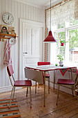 Rote Retrostühle um den Tisch vorm Fenster in der Landhausküche