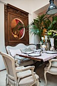 Set dining table and antique chairs below artistic wall panel