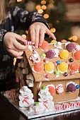 A girl decorating a gingerbread house with sweets