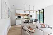 Grey sofa in front of open-plan kitchen with barstools at island counter
