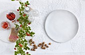 Rose hips and a white plate on top of a lace tablecloth