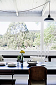 Black dining table with old church bench and chairs in light-flooded dining area