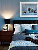 Doppelbett und Nachtkästchen mit Nachttischlampe im Schlafzimmer mit Holzverkleidung