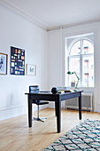 Dark desk and black leather chair in front of arched window