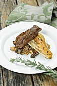 A fried rump steak with chicory and three varieties of mushrooms