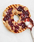 A grilled bagel with peanut butter and jam (close up)