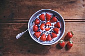 Frische Erdbeeren mit Joghurt und Kakaonibs in Schüssel (Aufsicht)