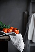 Ochsenherztomaten auf Tuch und Küchentisch in Landhausküche