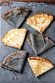Variety of black and white empty crepe pancakes, over gray metal background