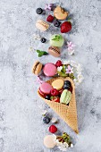 Variety of colorful french sweet dessert macarons with different fillings served in waffle cone with mint and fresh berries
