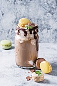 Chocolate coffee milkshake with ice cream scoop served in glass mason jar with a variety of macarons biscuit