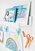 Kinderzeichnungen auf Wandboard und an einer Wäscheleine hängend im Kinderzimmer