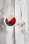 A mini smoothie bowl in a cup with berries and popped amaranth