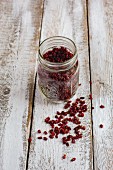 Dried goji berries in a glass jar on a wooden background