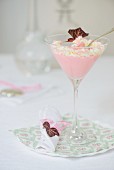 Pink crème dessert with whipped cream in a cocktail glass