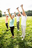 Four people exercising with hand weights in field