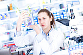 Scientist holding plant in beaker