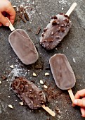 A chocolate and nut ice lolly with almonds, chocolate shavings and sea salt