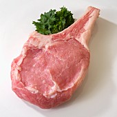 One raw Veal Chop on white with parsley