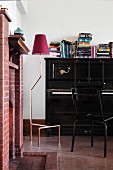 Brick fireplace, black piano and standard lamp in music room