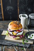 A lamb burger with hummus, mint yoghurt, and aubergine slices