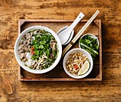 Pho Bo vietnamese Soup with beef in wooden tray on wooden background