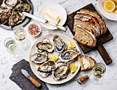 Open shucked Oysters with bread, butter and champagne on white marble background
